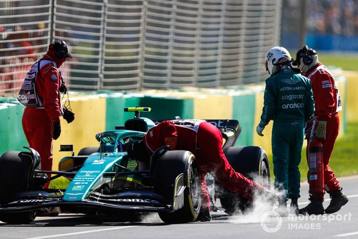 Oficiales de pista asisten a Sebastian Vettel, Aston Martin AMR22, tras abandonar en la FP1