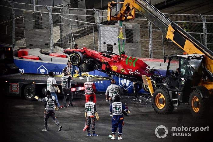 Los oficiales de pista retiran el coche dañado de Charles Leclerc, Ferrari SF21, del circuito