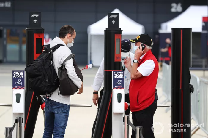 Robert Kubica, Alfa Romeo, muestra su pase a la entrada al paddock