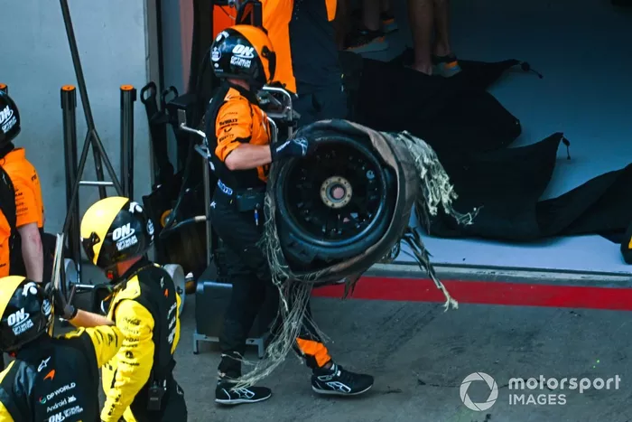 The damaged tyre is removed from the car of Lando Norris, McLaren MCL38