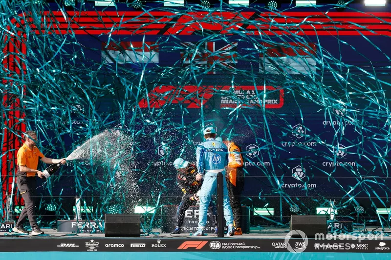 Max Verstappen, Red Bull Racing, 2e position, Lando Norris, McLaren F1 Team, 1re position, Charles Leclerc, Scuderia Ferrari, 3e position, célèbrent sur le podium avec du champagne alors que des serpentins tombent.