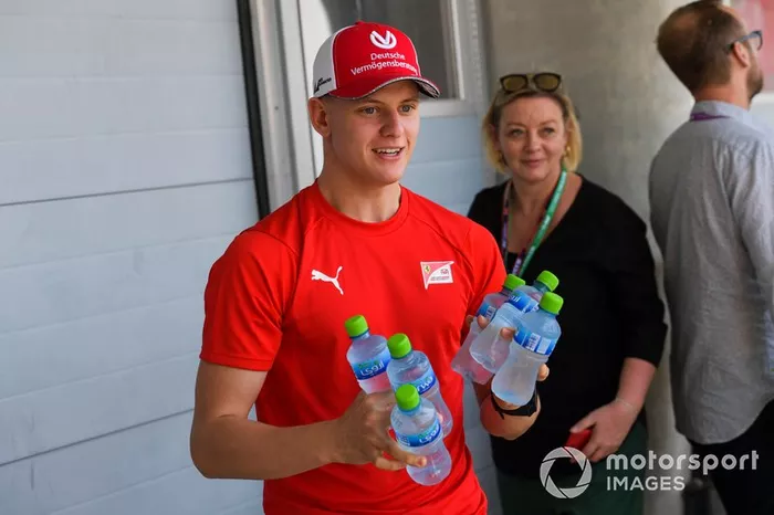 Mick Schumacher, brings the media bottles of water