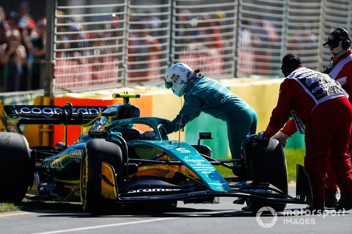 Oficiales de pista asisten a Sebastian Vettel, Aston Martin AMR22, tras abandonar en la FP1