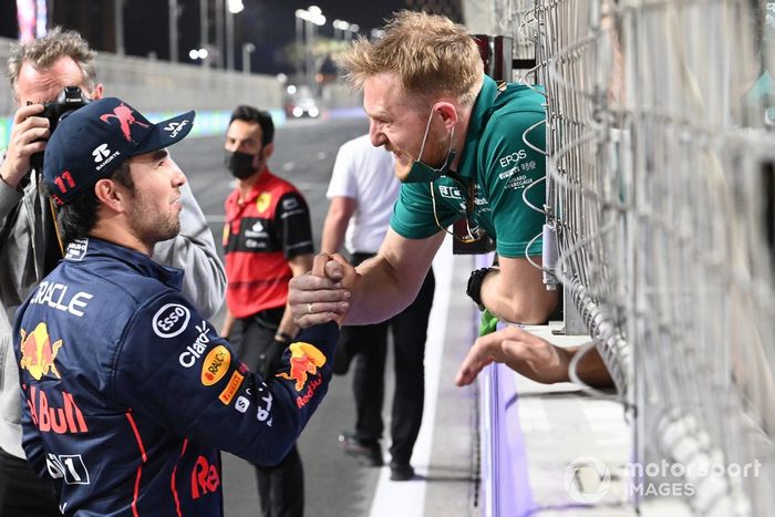 Un miembro del equipo Aston Martin felicita a Sergio Pérez, de Red Bull Racing, por conseguir la pole