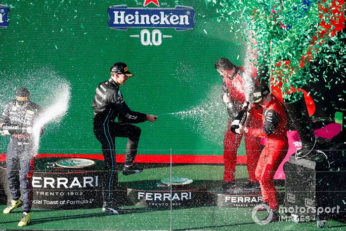 Sergio Pérez, Red Bull Racing, segundo, Charles Leclerc, Ferrari, primero, George Russell, Mercedes-AMG, tercero, y el representante de Ferrari celebran en el podio