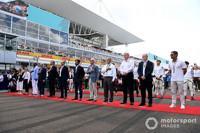 Dignatarios y pilotos se sitúan en la parrilla de salida para escuchar el himno nacional antes de la salida