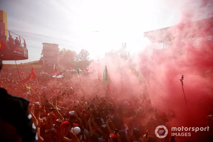 Una gran multitud se reúne y lanza bengalas de humo al final de la carrera