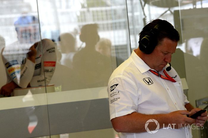 Fernando Alonso, McLaren observa a Zak Brown, Director Ejecutivo de McLaren, que utiliza su teléfono