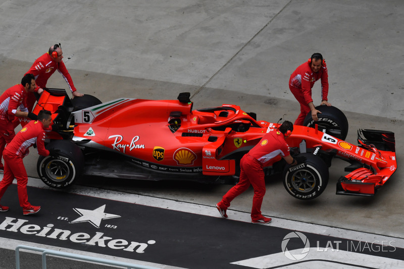 Des mécaniciens avec la Ferrari SF71H dans la voie des stands