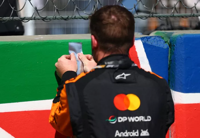 A McLaren team place a sticker on the grid