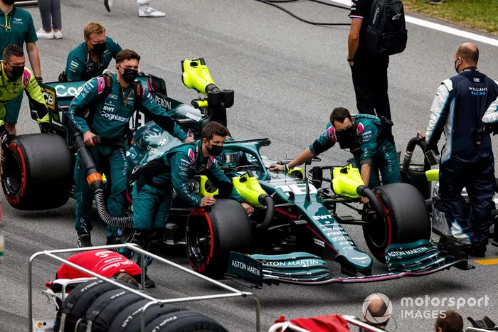 Los mecánicos mueven a Lance Stroll, Aston Martin AMR21, a su posición en la parrilla