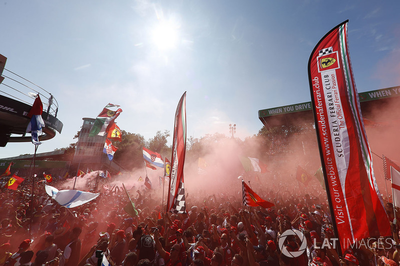 A sea of red clothes and red smoke gathers around the podium