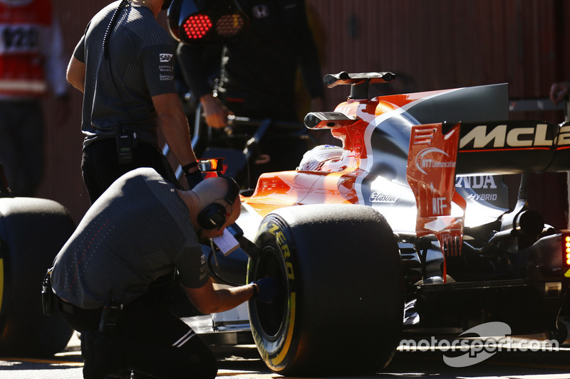 Un ingénieur Pirelli vérifie un pneu sur la voiture de Fernando Alonso, McLaren MCL32