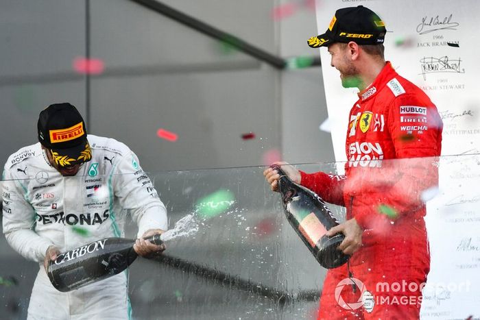 Lewis Hamilton, Mercedes AMG F1, secondo, e Sebastian Vettel, Ferrari, terzo, si spruzzano lo champagne sul podio