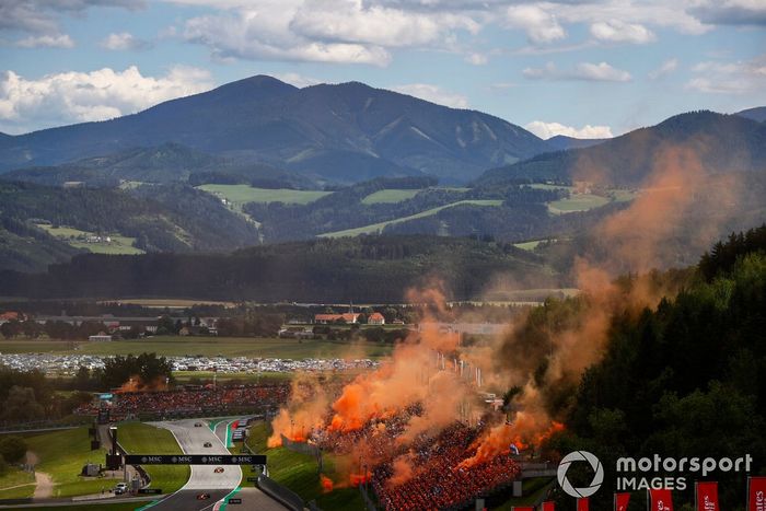 Lando Norris, McLaren MCL36, Daniel Ricciardo, McLaren MCL36, Lance Stroll, Aston Martin AMR22, mientras sale humo naranja de las gradas