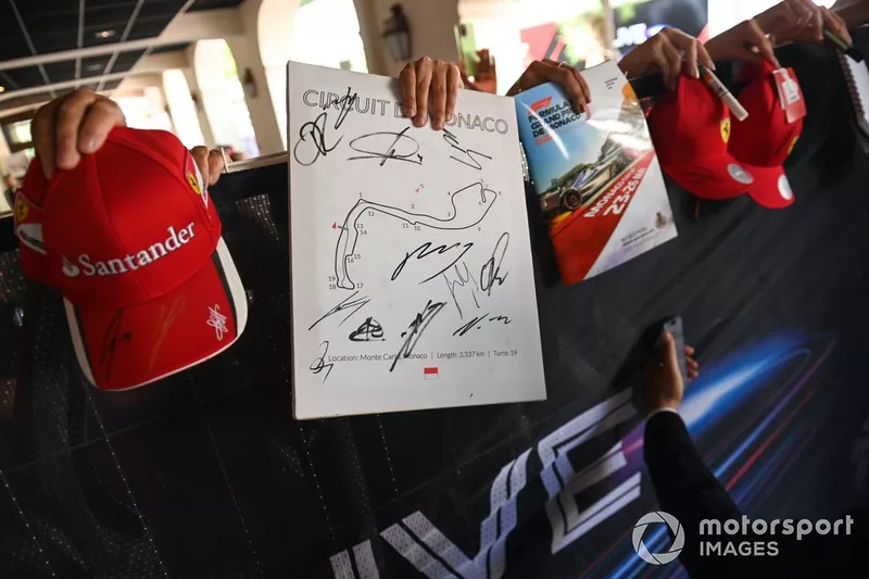 Les supporters tendent des casquettes et des programmes à signer