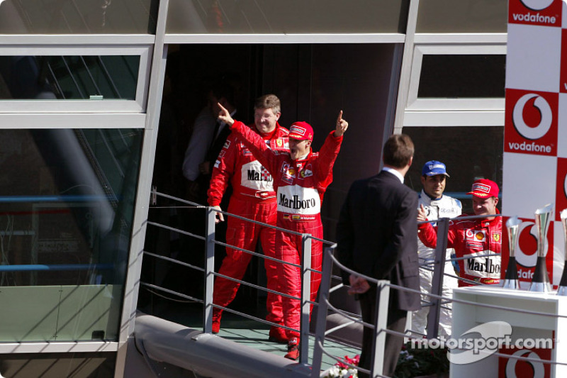 El ganador, Michael Schumacher y Ross Brawn celebran en su camino hacia el podium