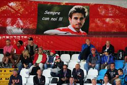 Aficionados en la tribuna principal con una bandera para Jules Bianchi