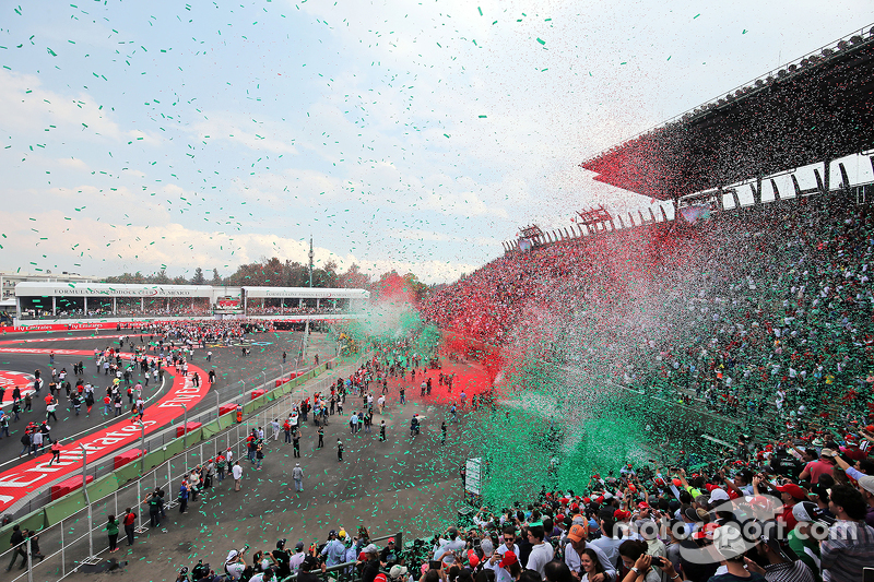 Ticker tape covers fans in the grandstand as the podium takes place